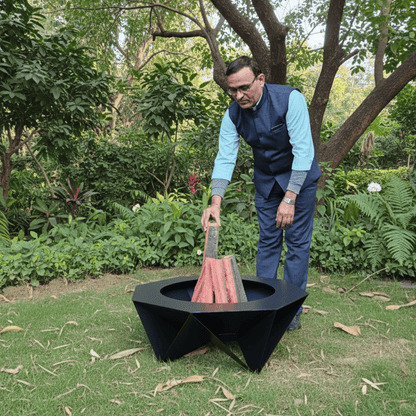 Man using a luxury Veranda by Metalit fire pit in a garden setting