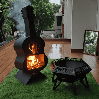 Guitar-shaped wood stove emitting smoke on a patio with green grass and trees in the background.
