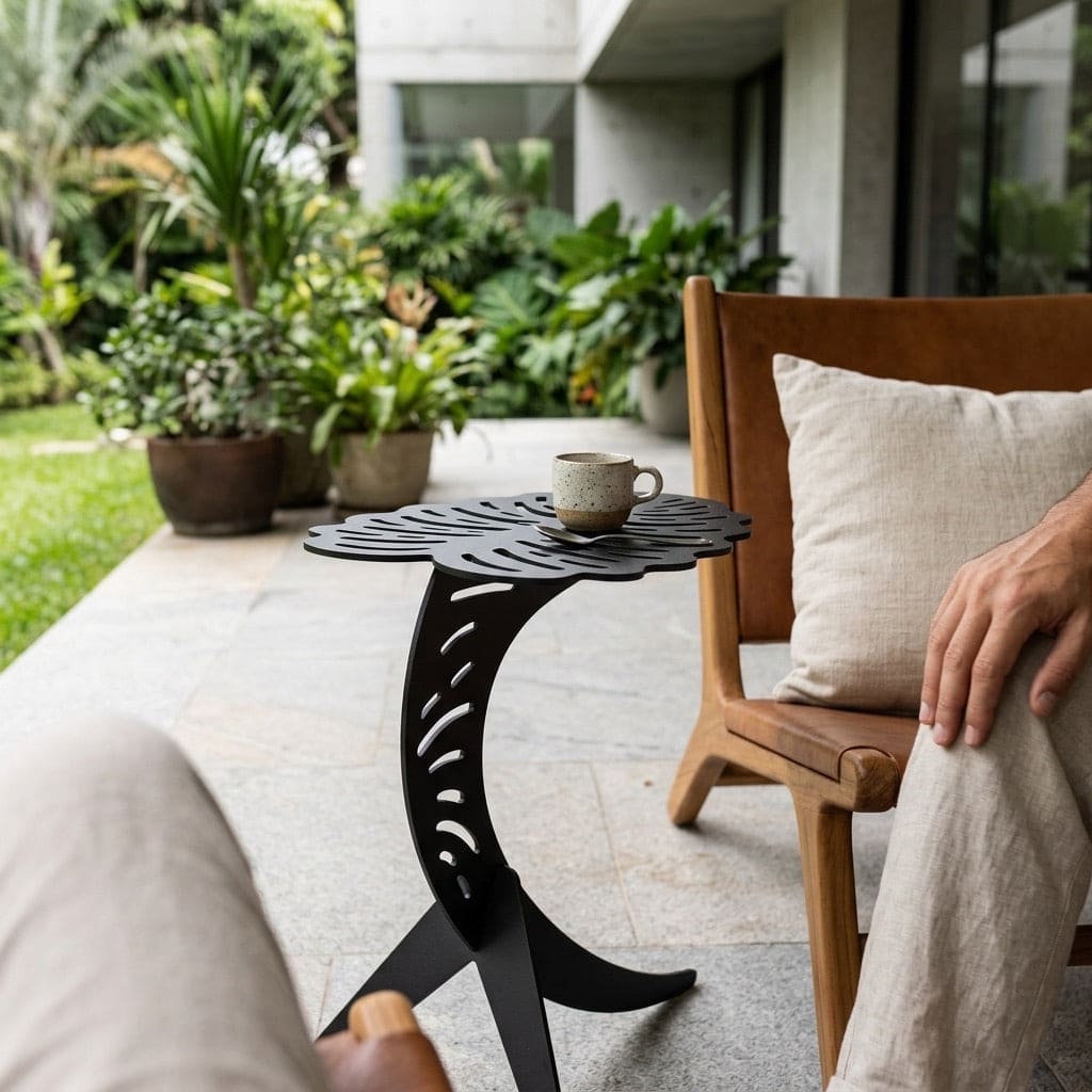 Person sitting on a wooden chair with a cushion, next to a luxury black side table with a mug on a patio.